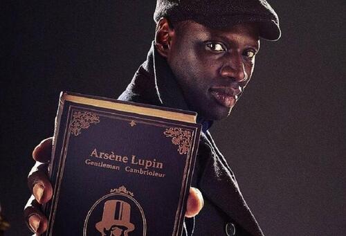 Imagen del actor que hace de Lupin en la serie homónima de Netflix sosteniendo el libro en el que se basa la adptación.